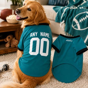 May include: A teal pet jersey with black trim featuring the white text ANY NAME above the number 00 on the back. A second identical teal jersey is displayed next to it, showing the text EST. 1995 JACKSONVILLE printed in white near the neckline.