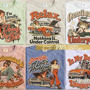 May include: Six t-shirts featuring graphic illustrations and text. Designs include a person at a desk, a person with a car, a cat at a typewriter, a person relaxing in a chair, a person walking away from a smoking car, and a raccoon in a car.