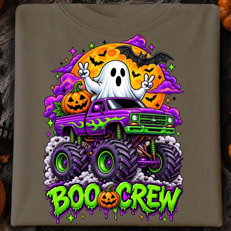 Puede incluir: Una camiseta color topo con un gr&aacute;fico de un fantasma blanco haciendo signos de paz, sentado en un cami&oacute;n monstruo morado con llamas verdes. Hay una luna naranja grande, murci&eacute;lagos, nubes moradas y una calabaza. El texto dice BOO CREW.