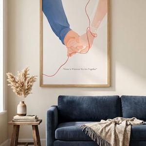 Könnte beinhalten: Gerahmter Kunstdruck mit einer Illustration von zwei Händen, die sich halten und durch eine rote Linie verbunden sind. Die Hände sind vor einem weißen Hintergrund dargestellt, mit dem Text "Home is Wherever We Are Together" unten. Der Rahmen ist aus Holz.