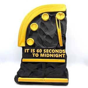 May include: A black and yellow Phaetons Clock sculpture with the text "IT IS 60 SECONDS TO MIDNIGHT". The clock has a textured, rocky appearance with yellow accents and circular details. The top of the clock is arched.