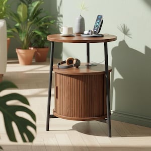 May include: A round, two-tiered side table with a dark wood finish and black metal legs. The top tier holds a phone, headphones, and a small vase. The bottom tier features a cabinet with a vertical slat design.