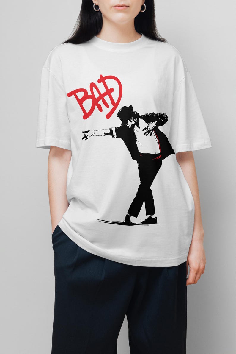 May include: White t-shirt featuring a black and red graphic of a person in a hat and suit, striking a dance pose. The word "BAD" is written in red above the figure.