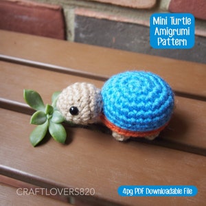 May include: A crocheted amigurumi turtle pattern. The turtle is blue, orange, and beige. The pattern is available as a 4-page PDF download. "Mini Turtle Amigurumi Pattern" is written in a blue box at the top of the image. "CRAFTLOVERS820" is written in the bottom left corner of the image. "4pg PDF Downloadable File" is written in the bottom right corner of the image.