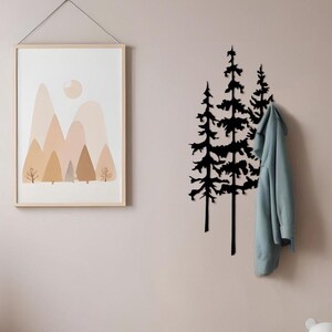 Pode incluir: Decoração de parede com silhueta de árvore preta com uma jaqueta azul clara pendurada. Uma impressão emoldurada de uma paisagem montanhosa está pendurada na parede. Duas cestas de vime e um bicho de pelúcia estão no chão.