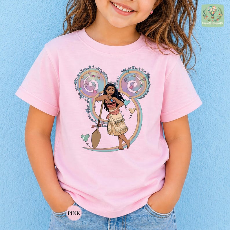 A young girl wearing a pink t-shirt with a Disney character printed on it, smiling at the camera.