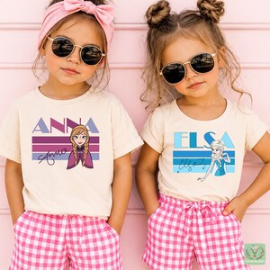 Two young girls wearing sunglasses and t-shirts with the character Anna from the Disney movie Frozen.