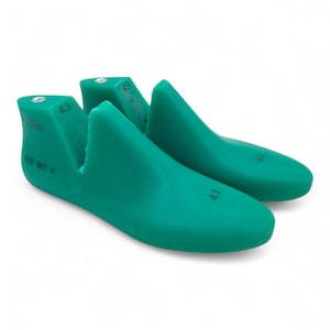 Puede incluir: Dos hormas de zapatos de color verde azulado, talla 43, sobre un fondo blanco. Las hormas son de un material liso y están diseñadas para dar forma a los zapatos. El número 43 está impreso en cada horma. La talla 43 es de unos 27 cm.