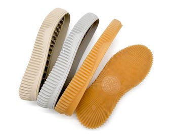 May include: Three shoe soles arranged side by side, featuring a beige sole, a light gray sole, and a tan sole. Each sole has a thick, ribbed sidewall and a textured bottom surface with a circular geometric pattern in the center of the tan sole.