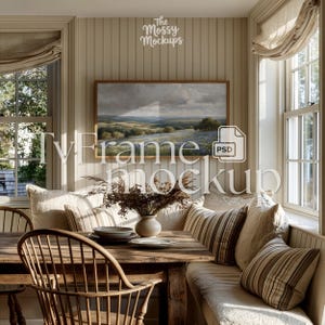 May include: A rustic dining room scene featuring a wooden table and chairs, a built-in bench with striped pillows, and a landscape painting. The room has a warm, inviting atmosphere with natural light and neutral tones. A vase of dried flowers sits on the table.