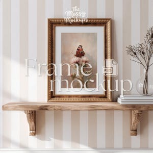 May include: A framed artwork featuring a butterfly on a flower, displayed on a wooden shelf. The frame is gold-colored with intricate detailing. The background is a striped pattern in beige and white. The text "Frame mockup" is overlaid on the image.