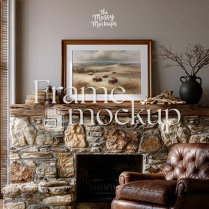 May include: A framed landscape painting featuring bison on a grassy plain hangs above a stone fireplace. The frame is brown, and the painting has a neutral color palette. The fireplace has a wooden mantel with decorative items, including a black vase and a vintage lantern. The words "Frame mockup" are overlaid on the image.