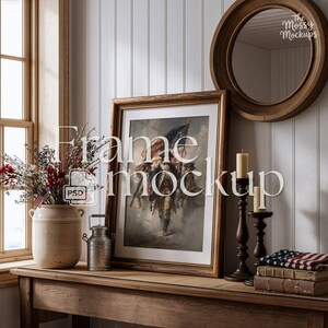 May include: A framed print of soldiers carrying a flag, displayed on a wooden table. The frame is gold-toned. A vase of flowers, a small metal container, and a stack of books are also on the table. The text "Frame mockup" is overlaid on the image.
