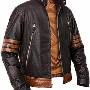 Könnte beinhalten: Eine dunkelbraune Lederjacke mit Stehkragen und Druckknopf, zwei vertikalen Reißverschlusstaschen auf der Brust sowie zwei horizontalen hellbraunen Streifen an jedem Ärmel. Die Jacke hat einen hellbraunen Saum und ein glattes beiges Innenfutter.