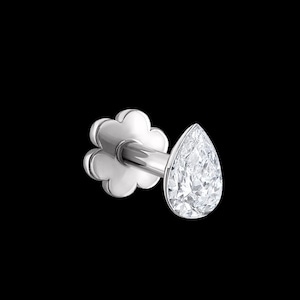 Puede incluir: Un pendiente de botón con parte posterior plana, que presenta una piedra preciosa transparente en forma de pera montada en un engaste de metal. La pieza trasera en forma de flor asegura el poste, proporcionando un ajuste firme para piercings.