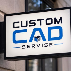 May include: A rectangular, wall-mounted, illuminated sign with a white background and a black frame. The text reads CUSTOM CAD SERVISE in black and blue, with a small blue and grey cube icon integrated into the letter A in the word CAD.