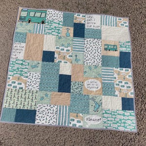 May include: A patchwork quilt with squares in teal, beige, and navy. The quilt features images of a bus and a pigeon, with text that reads "Don't Let the Pigeon Drive the Bus!" and "Please?" The quilt is approximately 120 cm x 120 cm.