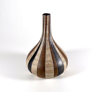 May include: A decorative vase with a bulbous body and a slender neck. The vase features vertical stripes in shades of brown, black, and beige. The vase is approximately 10 inches tall.