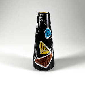 May include: A black ceramic vase with abstract designs. The vase has a yellow rim and is decorated with a blue spiral, a yellow triangle, and a brown, textured shape. White lines and shapes add to the artistic design.