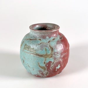 May include: A small, round ceramic vase with a mottled glaze in shades of blue, green, and red.