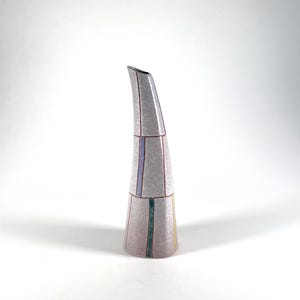 May include: A tall, decorative vase with a slender, curved spout. The vase is primarily light pink with vertical stripes in shades of purple, green, and yellow. The design is geometric and modern, suitable for home decor.