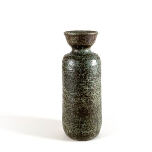 K&ouml;nnte beinhalten: Eine hohe, gr&uuml;ne Keramikvase mit einer gesprenkelten braunen Glasur. Die Vase hat einen breiten, abgerundeten Boden und einen schmalen Hals.