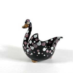 Puede incluir: Macetero de cerámica negro en forma de cisne con lunares rosas y blancos. El cisne tiene un pico pequeño y un cuerpo redondo.