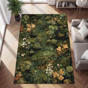 Puede incluir: Una alfombra rectangular con un diseño botánico. La alfombra presenta un patrón denso de follaje verde, con acentos de flores doradas y blancas. La alfombra está colocada sobre un suelo de madera.