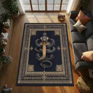 Op de afbeelding: Een rechthoekig vloerkleed met een ontwerp van een opgerolde cobra. Het kleed heeft een donkerblauwe achtergrond met een gouden rand en accenten. De cobra is afgebeeld in grijstinten en bruin, met zijn kap omhoog.
