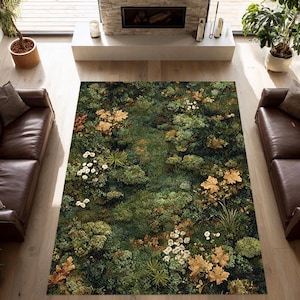 May include: A rectangular rug with a detailed botanical design. The rug features a dense pattern of green foliage, interspersed with white flowers and golden-brown leaves. The rug is placed on a light-coloured wooden floor, with brown leather sofas on either side.