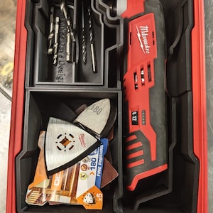 以下が含まれることがあります： 赤と黒のミルウォーキー電動工具キット。マルチツール、ドリルビット、サンディングパッドなどのアクセサリーが含まれています。ケースは赤色で、黒色のコンパートメントと透明な蓋が付いています。マルチツールにはミルウォーキーのロゴがあります。