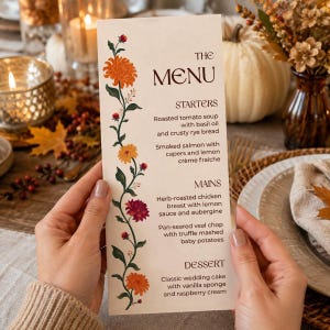 May include: A tall, rectangular menu card with a cream background, featuring a vertical floral vine illustration with orange, yellow, and deep red chrysanthemums on the left. The text lists starters, mains, and dessert options in dark brown font.