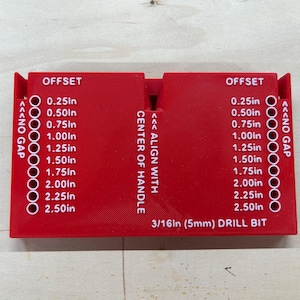 May include: A red plastic drill bit offset guide with white text indicating measurements from 0.25in to 2.50in. The text "OFFSET" is at the top, and "3/16in (5mm) DRILL BIT" is at the bottom.