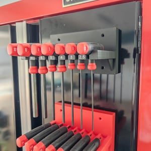 May include: A Craftsman tool cabinet featuring two wall-mounted organizers holding sets of hex keys. The top grey organizer holds metric keys labeled 10, 8, 6, 5, 4, 3, and 2.5. The bottom red organizer holds imperial keys labeled 1/4, 7/32, 3/16, 5/32, 1/8, 3/32, and 5/64.