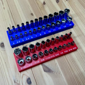 May include: A blue plastic socket organizer tray holding metric steel sockets labeled 4 through 14, and a red plastic socket organizer tray holding imperial steel sockets labeled 9/16 through 5/32, both featuring clearly printed size markings.