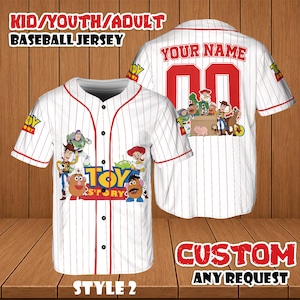 May include: White baseball jersey with red pinstripes and accents, featuring Toy Story characters. The jersey has the text "TOY STORY" on the front and "YOUR NAME" and the number "00" on the back. The jersey is available in kid, youth, and adult sizes.