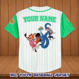 May include: White baseball jersey with green sleeves and collar. Features a cartoon graphic of a fox, rabbit, and snake. The text "YOUR NAME" is printed across the back in green. Vertical green stripes run down the front.