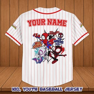 May include: White baseball jersey with red pinstripes, featuring a colorful Spider-Man graphic on the back. The jersey has red trim and the text "YOUR NAME" above the graphic. The bottom of the jersey reads "KID, YOUTH BASEBALL JERSEY".