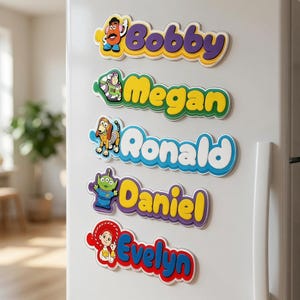 May include: Five custom name magnets arranged vertically on a white refrigerator. Each magnet features a colorful cartoon character from the Toy Story franchise next to a name in bold, raised lettering: Bobby, Megan, Ronald, Daniel, and Evelyn.