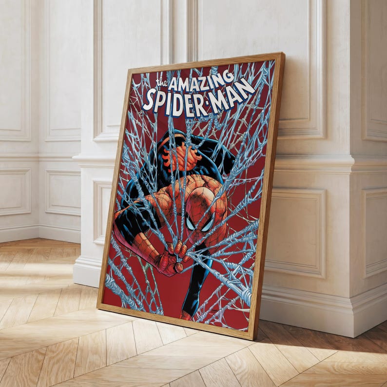 K&ouml;nnte beinhalten: Gerahmter Comic-Kunstdruck mit Spider-Man in einer dynamischen Pose, umgeben von seinem Netz. Der Titel "The Amazing Spider-Man" ist oben zu sehen. Das Kunstwerk hat einen roten Hintergrund und einen Holzrahmen.