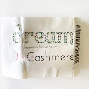 May include: A white label with the word "dream" in colorful letters, the website "dreamincoloryarn.com", and the text "Jilly with Cashmere".