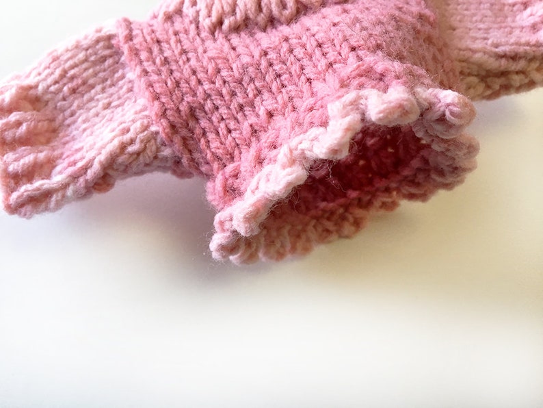 May include: A pink knitted sweater with a ruffled edge.