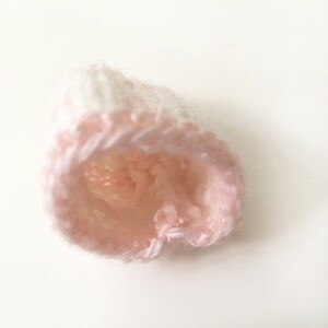 Puede incluir: Un gorro de punto rosa y blanco con una textura suave y esponjosa.