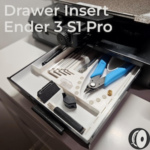 May include: A white and black drawer insert for an Ender 3 S1 Pro 3D printer, filled with tools. The drawer contains a variety of tools, including Allen keys, wire cutters with blue handles, and other small parts. The text "Drawer Insert Ender 3 S1 Pro" is visible.