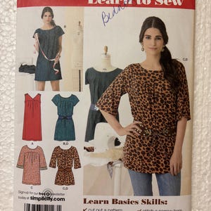 May include: Simplicity sewing pattern 2147 for sizes 6-18. The envelope features illustrations of a dress and top with various sleeve lengths, necklines, and belt options. Text includes Learn to Sew, Learn Basics Skills, and a barcode.