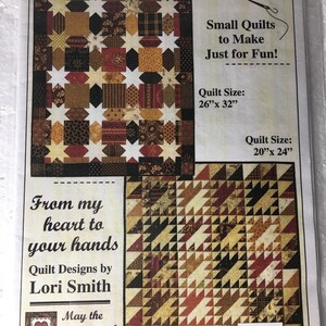 May include: A flyer for "Quaint Little Quilts #7" featuring two quilt designs. One quilt is 26" x 32" with star and square patterns in brown, tan, and burgundy fabrics. The other quilt is 20" x 24" with a triangle pattern. Text includes "Small Quilts to Make Just for Fun!" and "Quilt Designs by Lori Smith."
