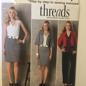 May include: Simplicity sewing pattern featuring three women's fashion ensembles. The pattern includes a white top and gray skirt, a gray suit with a floral accent, and a red jacket with black pants. The text reads "threads MAGAZINE COLLECTION".