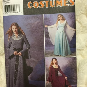 May include: Simplicity Costumes pattern featuring medieval-style dresses. The pattern includes designs for long gowns with flared sleeves and decorative trim. The package displays images of the finished costumes, showcasing the different styles and colors available.