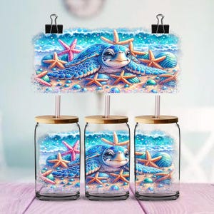 May include: Three glass beverage jars with bamboo lids and straws. Each jar features a vibrant illustration of a sea turtle, starfish, and seashells on a sandy beach with ocean waves. The design is attached to the jars with binder clips.