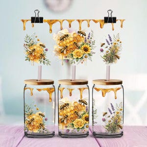 Peut inclure: Trois verres transparents avec couvercles en bambou et pailles, chacun orné d'un motif de rayons de miel, tournesols jaunes, brins de lavande et abeilles, avec un motif décoratif de miel coulant sur le bord supérieur de chaque verre.